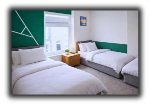 a room with two beds and a green wall at Pitchside House Walk to Anfield sleeps 7 in Liverpool +3 photos