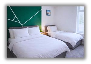 two beds in a room with a green wall at Pitchside House Walk to Anfield sleeps 7 in Liverpool