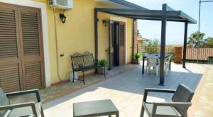 a patio with a table and chairs and a building at Sotto i Monti House in Nicolosi