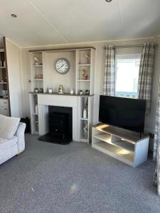 a living room with a fireplace and a clock at haven kent coast in Allhallows