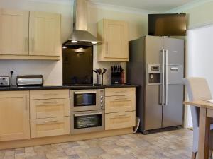 a kitchen with a stainless steel refrigerator and cabinets at The Oaks - Uk11270 in Lanreath +14 photos