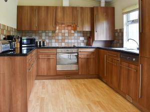 a kitchen with wooden cabinets and a stove top oven at The Lodge - Uk11271 in Lanreath