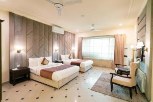 a hotel room with two beds and a chair at Shelton Rezidor House F-8 Islamabad in Islamabad
