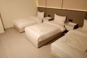 a hotel room with two beds and two ottomans at رست للشقق المخدومة in Medina +4 photos
