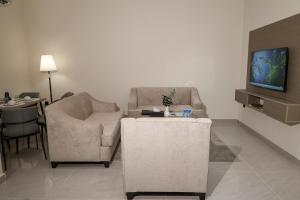 a living room with two chairs and a tv at رست للشقق المخدومة in Medina