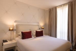 a bedroom with a large white bed with two red pillows at Hotel Renoir in Cannes