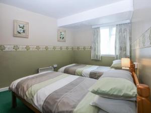 a bedroom with two beds and a window at First Floor Apartment in Porthmadog