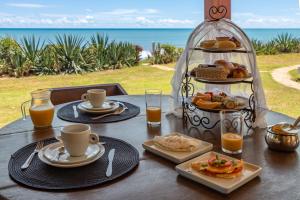 a table with food and drinks on it with the ocean at Pousada Spa dos Amores in São Miguel do Gostoso