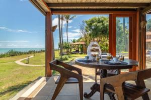 a table and chairs on a patio with a view of the ocean at Pousada Spa dos Amores in São Miguel do Gostoso +84 photos
