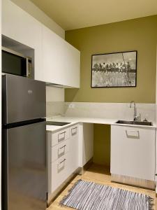a kitchen with white cabinets and a stainless steel refrigerator at the window in Domodossola