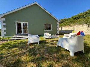 a green house with chairs and a table in the yard at Christinas Cottage Downpatrick in Raholp +17 photos