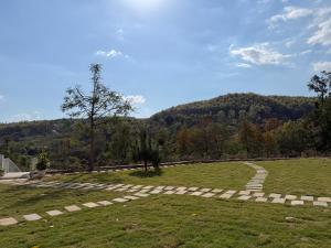 a grassy field with a stone pathway in front of a mountain at Saraiville- A Boutique Riverside Resort in Dehradun