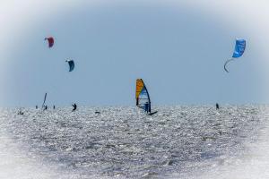 a group of people flying kites in the ocean at Am Sahlenburger Strand AS23 in Cuxhaven