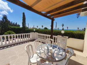 a patio with a glass table and chairs and the ocean at Villa Arfa in Peyia