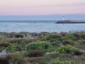 a beach with a lighthouse in the water at Appartement 30 m de la mer in La Turballe