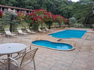 a swimming pool with chairs and a table and flowers at Pousada Juriti - Eco Hotel in São Roque