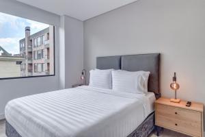 a white bedroom with a large bed and a window at Hotel EspacioYa By Mario Rental 103 in Bogotá