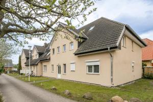 a white house with a black roof on a street at FeWo Dock12C in Kölpinsee