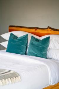 a white bed with three blue pillows on it at Hot Tub Nights & Mountain Mornings PÜR in Golden