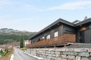 a black house on a stone wall next to a road at Aurora Apartments - Stryn View in Stryn