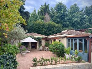 a house with a patio with chairs and trees at Penny Royal Guest Cottages in Somerset West