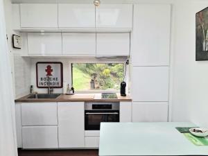 a kitchen with white cabinets and a sink and a window at Independent studio in Pont-lʼAbbé