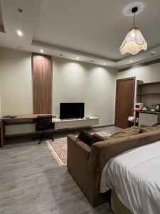 a bedroom with a couch and a desk with a television at black tiger villa in ‘Ezbet `Abd el-Ḥamîd