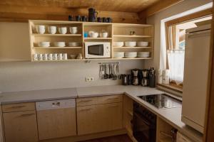 eine Küche mit Holzschränken und einer Mikrowelle in der Unterkunft Appartement Catrin mit Wellnessbereich und Aroma-Anwendungen in Ried im Zillertal