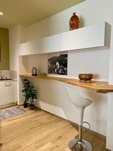 a kitchen with white cabinets and a bar with a stool at the window in Domodossola +8 photos