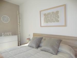 a bedroom with a white bed with a picture on the wall at Somnis del Delta, Apartamento Deltebre, Delta Ebro in Deltebre