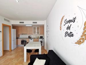 a living room with a white table and a kitchen at Somnis del Delta, Apartamento Deltebre, Delta Ebro in Deltebre