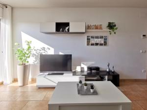 a white living room with a tv and a couch at Somnis del Delta, Apartamento Deltebre, Delta Ebro in Deltebre