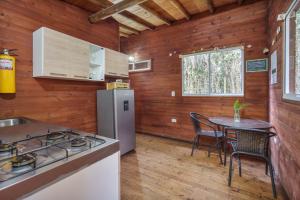 a kitchen with a stove and a table with chairs at Cabañas La Silleta in Santa Elena