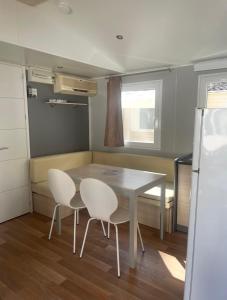 a small kitchen with a table and two white chairs at Mobilhome Ligaropa climatisé 3 ch 6 pers camping des 7 fonts in Agde +13 photos