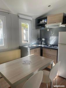 a kitchen with a wooden table and two chairs at Mobilhome Ligaropa climatisé 3 ch 6 pers camping des 7 fonts in Agde