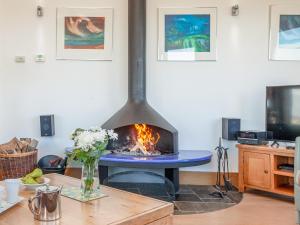 a fireplace in a living room with a table at Shark Fin in Sennen
