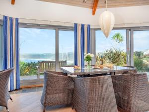 a dining room with a table and chairs and windows at Shark Fin in Sennen +35 photos