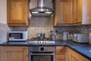 a kitchen with a stove and a microwave at Charming & Cosy Drymen Flat in Drymen
