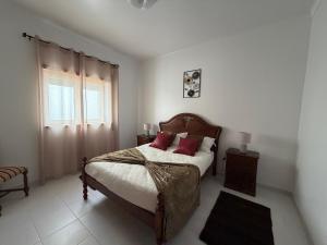 a bedroom with a bed with red pillows and a window at Casa da Tininha in Alcobaça