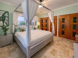 a bedroom with a canopy bed and a window at 1 min walk beach,bars,grocery in Punta Cana +14 photos