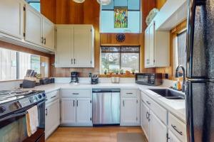 a kitchen with white cabinets and a black refrigerator at Prentiss Retreat in Sea Ranch