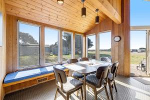 a dining room with a table and chairs and windows at Samson Getaway in Sea Ranch