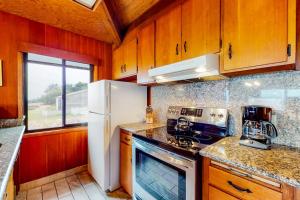 a kitchen with wooden cabinets and a white refrigerator at Comstock Retreat in Sea Ranch