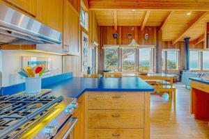 a large kitchen with a blue counter top and wooden ceilings at Gewing House in Sea Ranch
