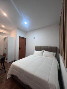 a bedroom with a large white bed and a table at The Haven Suites Batam in Tanjunguma