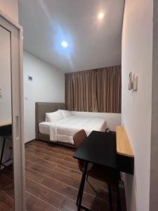 a bedroom with a bed and a table and a desk at The Haven Suites Batam in Tanjunguma