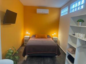 a bedroom with yellow walls and a bed and shelves at Aqui es 6! in Banfield