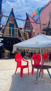a group of red chairs and a table with an umbrella at Tipiland baru la casa del mono in Playa Blanca