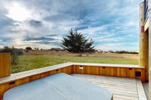 a bed on a wooden deck with a view of a field at Seas the Day in Sea Ranch
