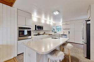 a kitchen with white cabinets and a large island with stools at Tree House in Sea Ranch